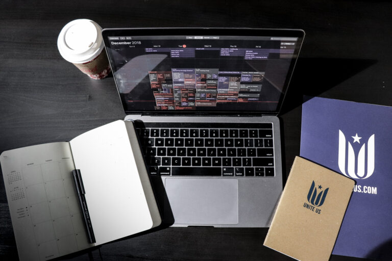 Laptop surrounded by Unite Us swag