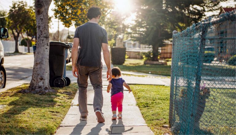 father walking with daughter on sidewalk