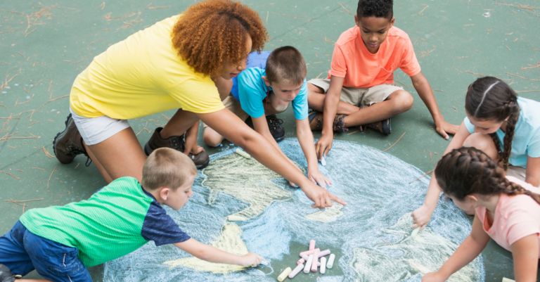 young children create sidewalk chalk art while teacher points