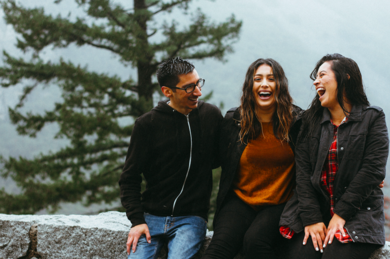 group shot of people laughing and smiling on scenic ledge