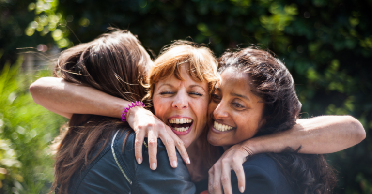 3 women smiling and hugging